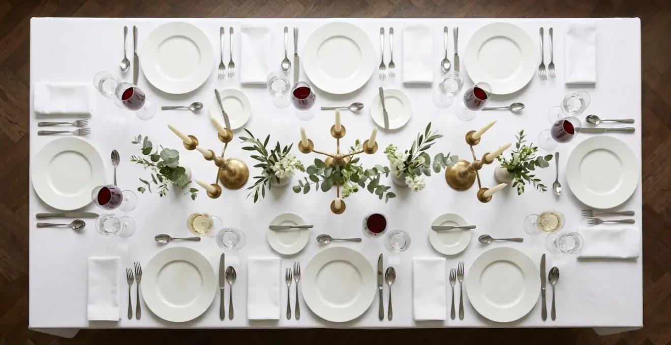 Vue aérienne d'une table dressée avec élégance, cristal et argenterie disposés symétriquement