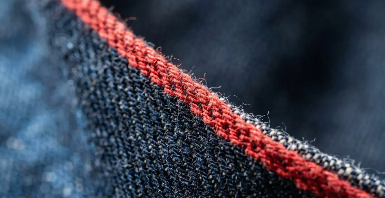 Détail macro d'une lisière selvedge rouge montrant la texture du tissage serré